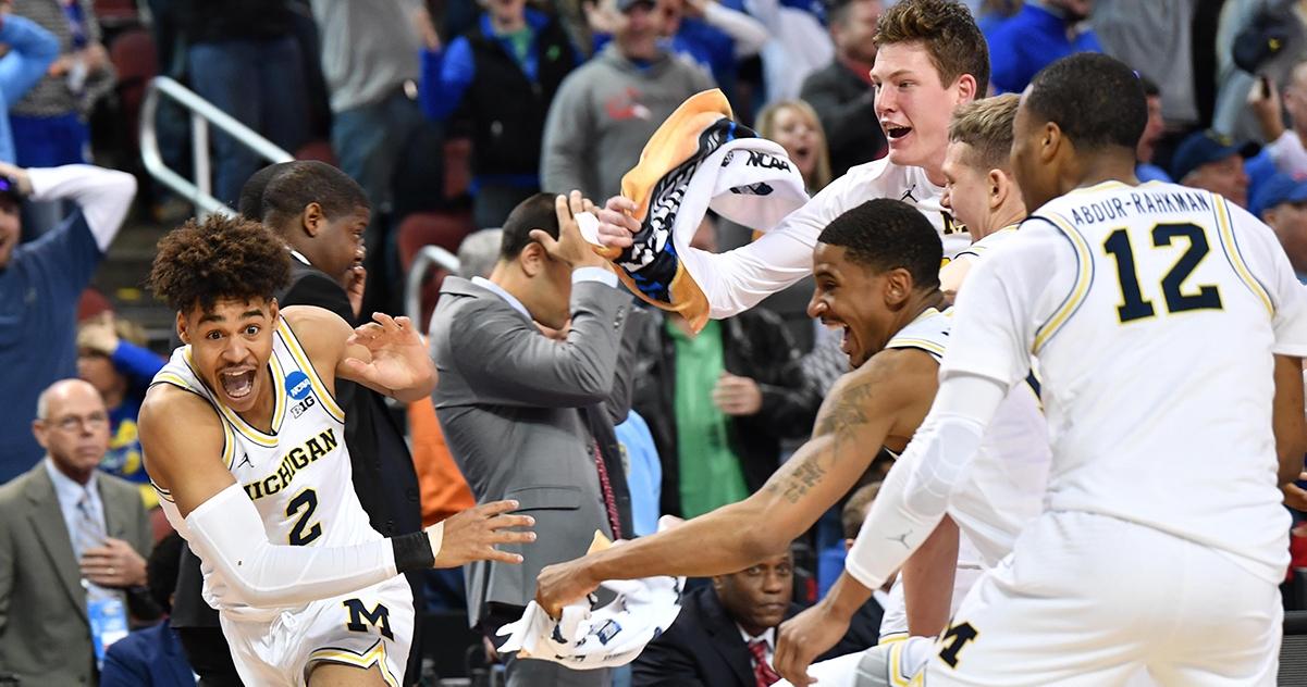 Michigan's Jordan Poole runs from teammates.