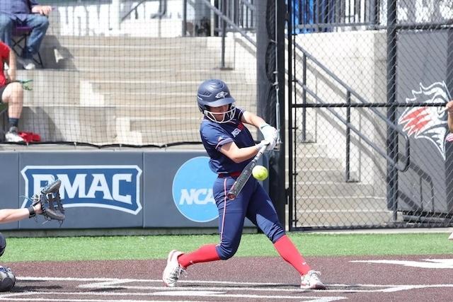 An MSU Denver softball player in a home blue jersey barrels up on a ball. 